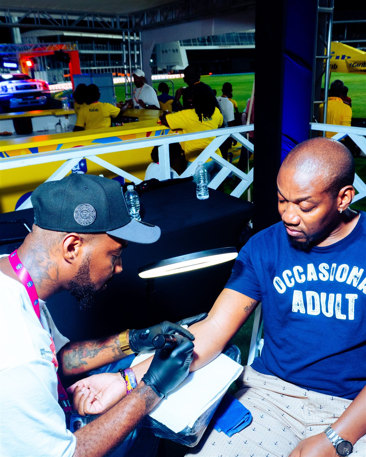 Sav The Creator tattooing a client's forearm at an event stand