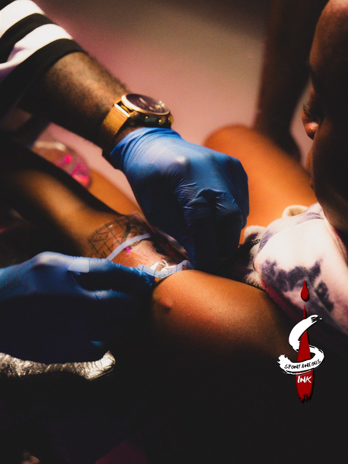 Gloved hands tattooing under warm studio light
