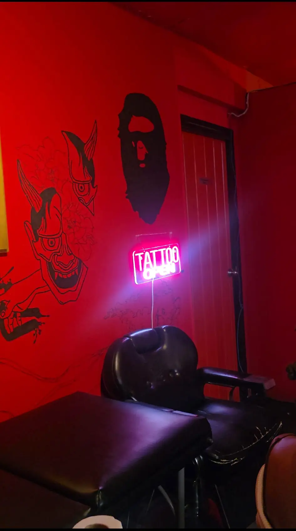 A second view of the red studio's mural wall, chair and neon sign