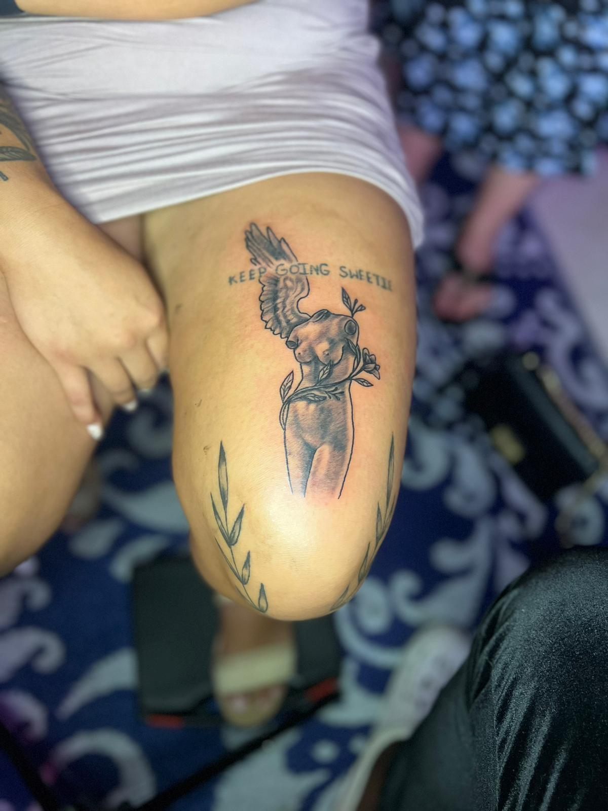 Winged torso statue with script lettering, black and grey, thigh