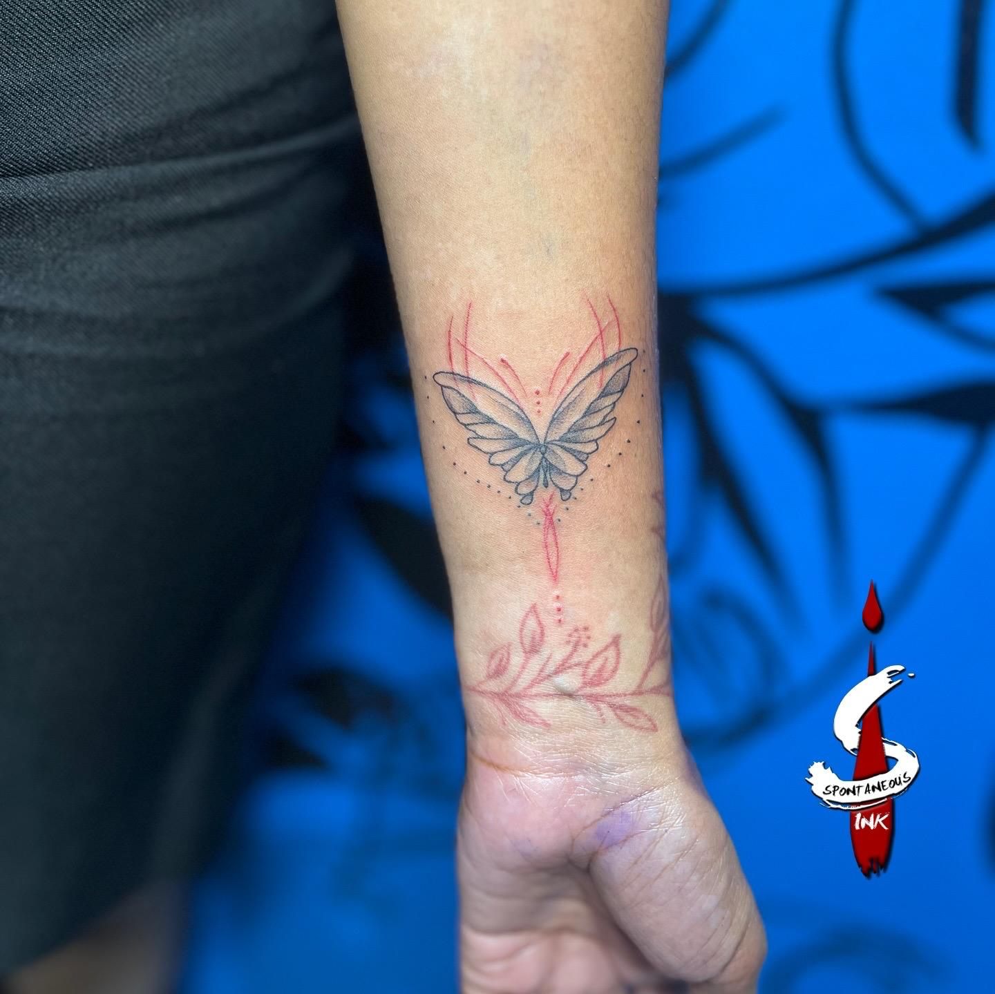 Fine-line butterfly with red linework accents, wrist