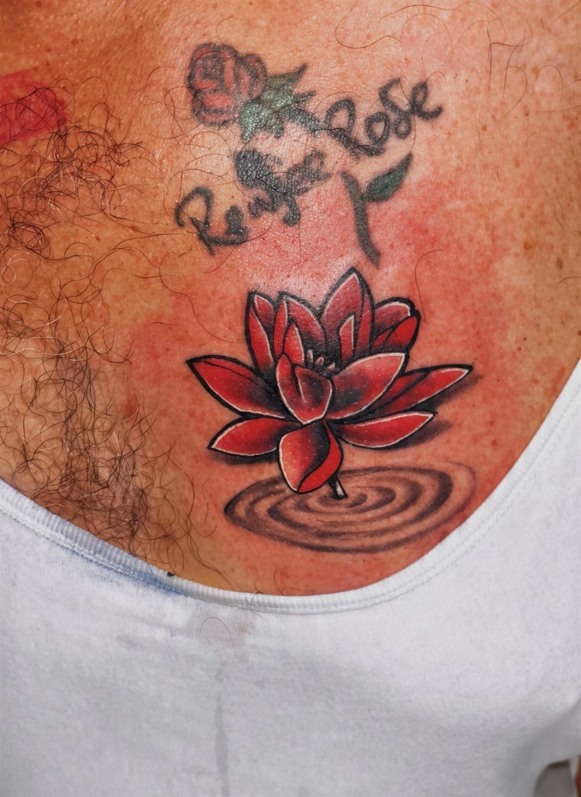 Red lotus over rippling water covering earlier lettering, colour, chest